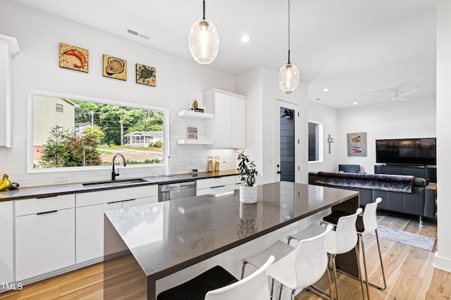 kitchen with decorative backsplash, a kitchen breakfast bar, visible vents, and a sink