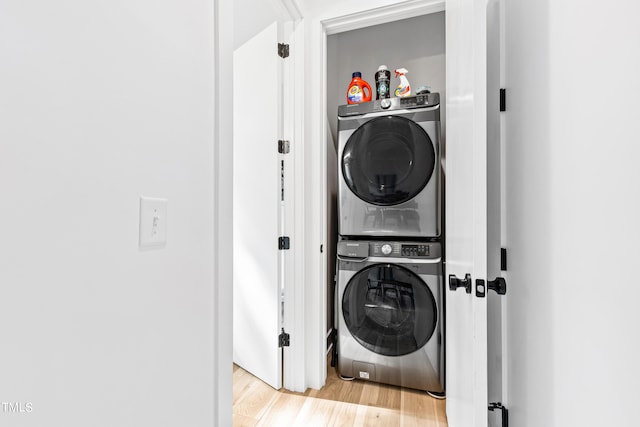 clothes washing area featuring laundry area, light wood-style flooring, and stacked washer / drying machine