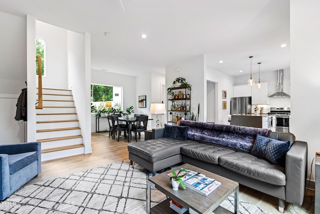 living room featuring recessed lighting, light wood-style flooring, and stairs