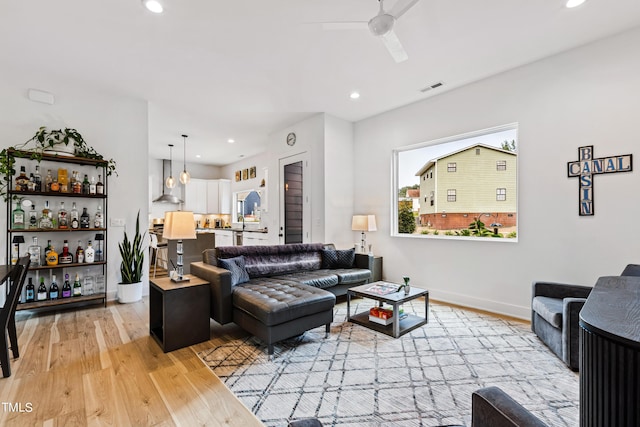 living room with a bar, visible vents, ceiling fan, light wood-style floors, and recessed lighting