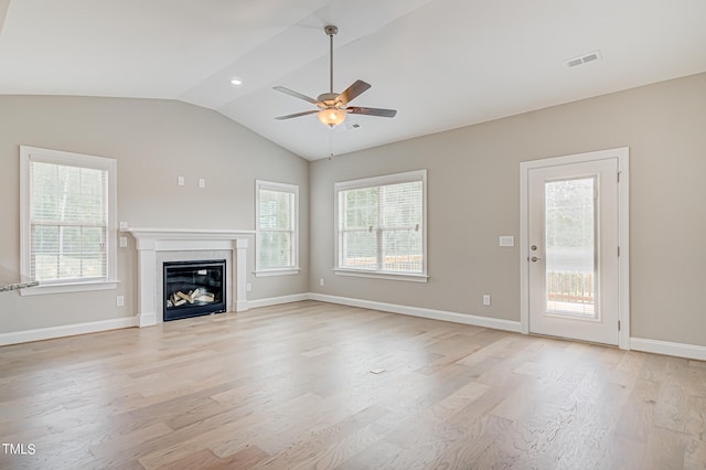 unfurnished living room featuring a healthy amount of sunlight, light hardwood / wood-style floors, vaulted ceiling, and ceiling fan