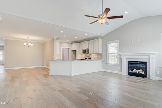 unfurnished living room with light wood-type flooring, lofted ceiling, sink, ornamental molding, and ceiling fan with notable chandelier