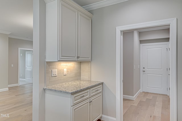 kitchen featuring crown molding, light hardwood / wood-style floors, and tasteful backsplash