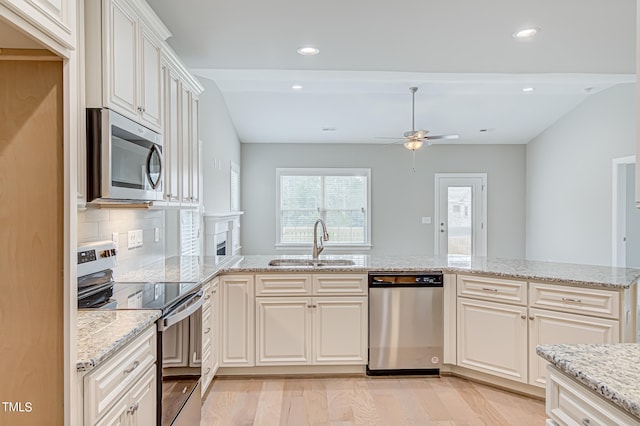 kitchen featuring appliances with stainless steel finishes, decorative backsplash, light stone counters, light hardwood / wood-style flooring, and sink