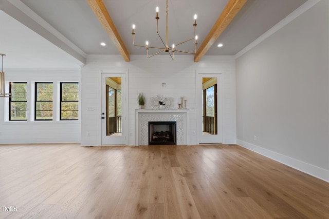 unfurnished living room with a fireplace, light hardwood / wood-style flooring, a chandelier, and beam ceiling