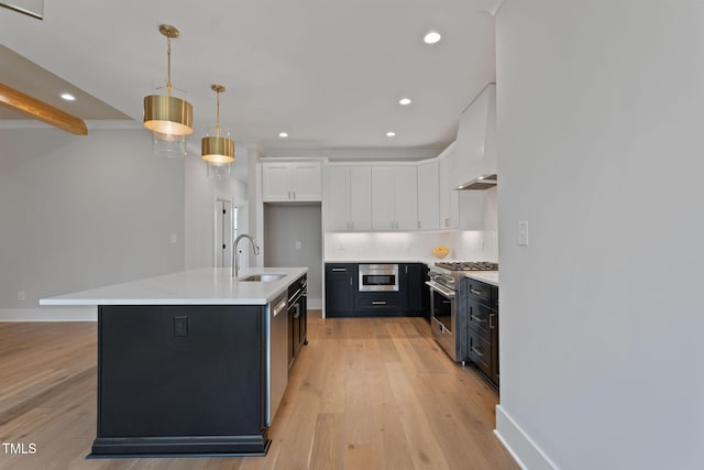 kitchen featuring white cabinetry, appliances with stainless steel finishes, pendant lighting, an island with sink, and light hardwood / wood-style flooring