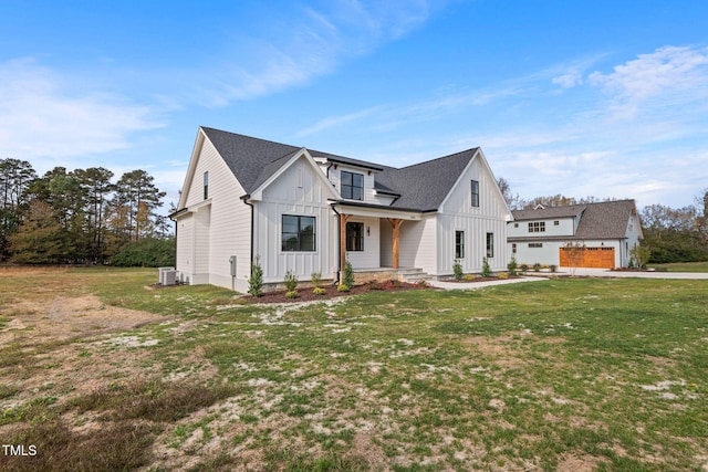 modern farmhouse style home with a garage, a porch, a front yard, and central AC unit