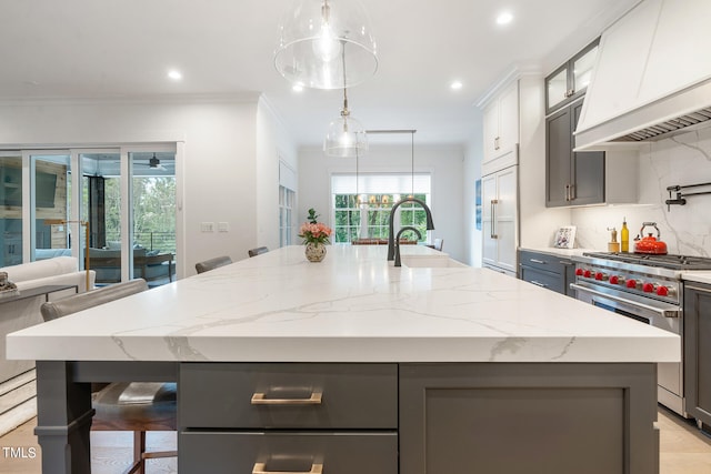 kitchen featuring a kitchen island with sink, sink, a wealth of natural light, and high end appliances