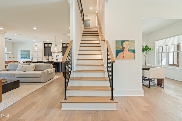 stairway featuring ornamental molding, sink, and hardwood / wood-style floors