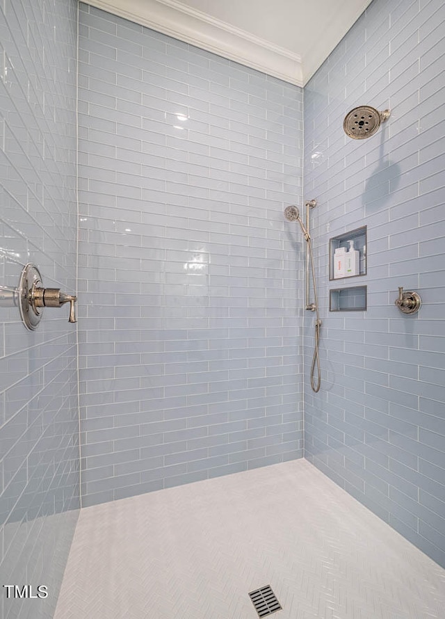 bathroom featuring ornamental molding and a tile shower