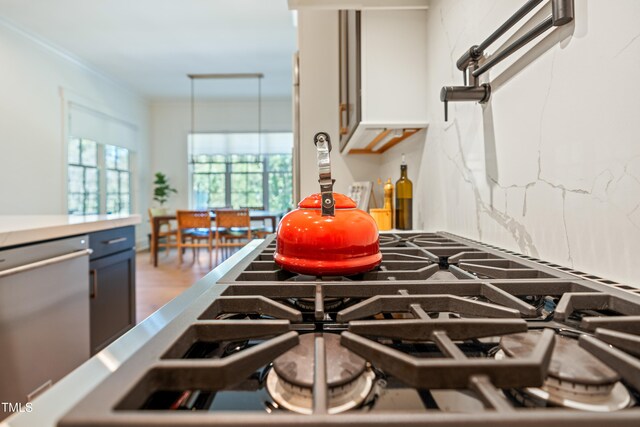 kitchen featuring crown molding, backsplash, hardwood / wood-style flooring, and stainless steel dishwasher