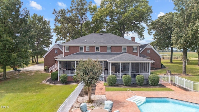 back of property featuring a yard, a sunroom, and a fenced in pool