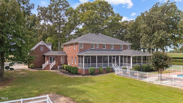 back of property with a sunroom, a lawn, and central AC unit