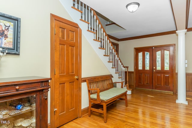 entrance foyer with light hardwood / wood-style floors, ornamental molding, and ornate columns