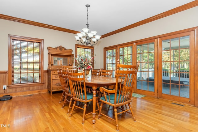 dining space with crown molding, a notable chandelier, a wealth of natural light, and light hardwood / wood-style floors