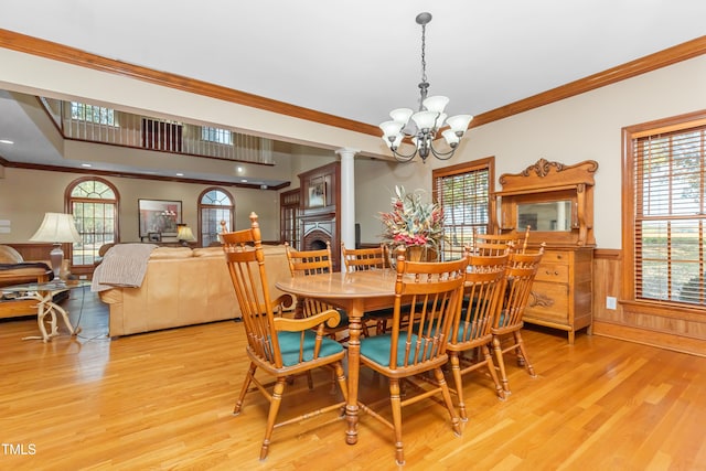 dining area with light hardwood / wood-style floors, crown molding, and an inviting chandelier