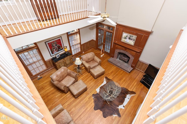 living room featuring a towering ceiling, hardwood / wood-style flooring, a fireplace, and ceiling fan