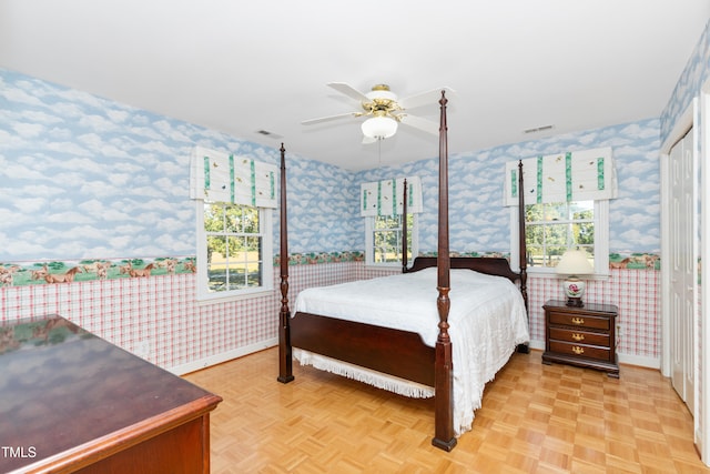 bedroom featuring multiple windows, light parquet floors, and ceiling fan