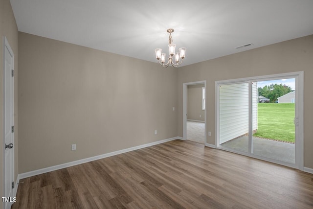 spare room featuring a chandelier and hardwood / wood-style floors