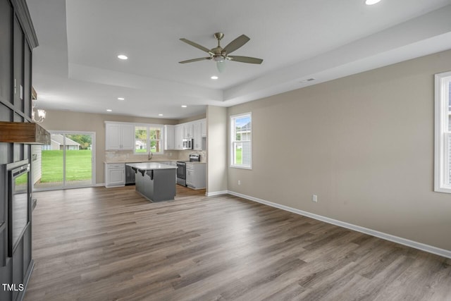 kitchen with stainless steel appliances, white cabinetry, a center island, and a healthy amount of sunlight