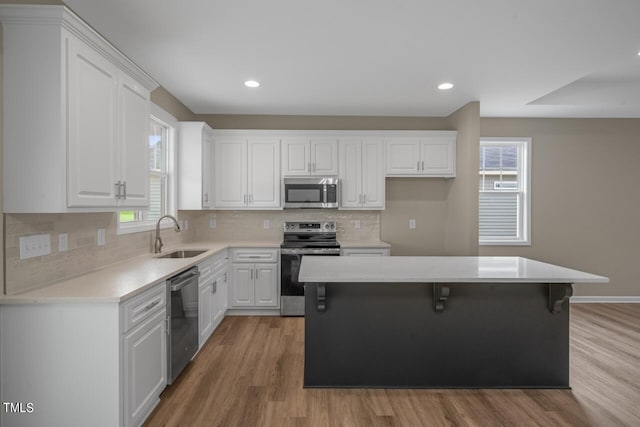 kitchen with stainless steel appliances, a center island, a healthy amount of sunlight, and sink