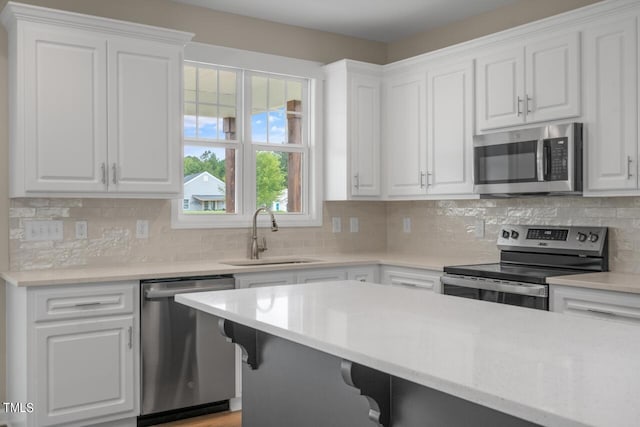 kitchen featuring stainless steel appliances, white cabinetry, tasteful backsplash, and sink