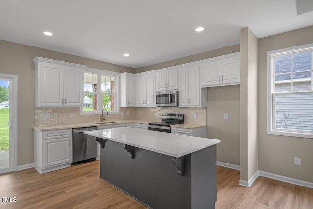 kitchen featuring stainless steel appliances, white cabinetry, and a wealth of natural light