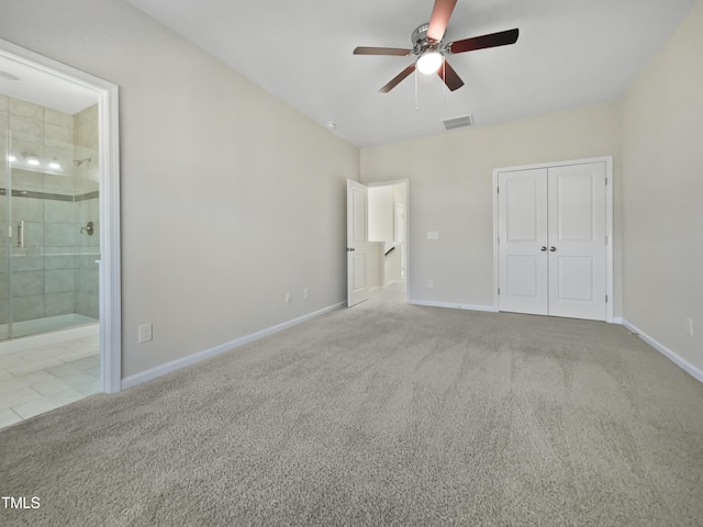 unfurnished bedroom with ceiling fan, a closet, light colored carpet, and ensuite bath