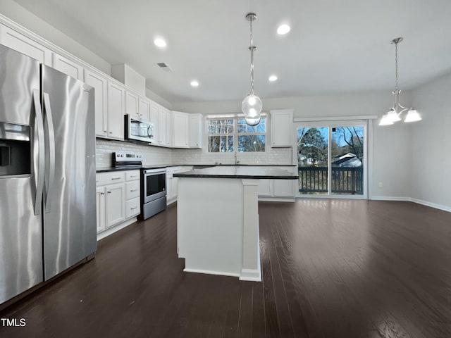 kitchen with white cabinets, stainless steel appliances, and decorative light fixtures