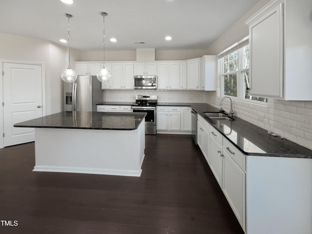 kitchen featuring a center island, sink, stainless steel appliances, dark hardwood / wood-style floors, and white cabinets