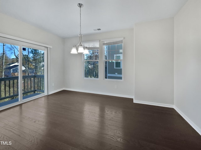 spare room featuring a chandelier and dark hardwood / wood-style flooring