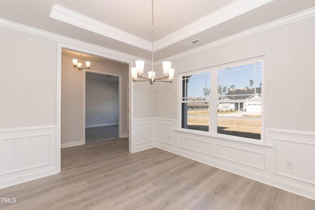 unfurnished dining area with hardwood / wood-style floors, ornamental molding, and a chandelier