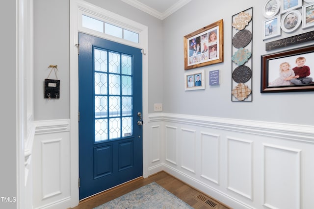 doorway to outside with ornamental molding, wainscoting, wood finished floors, and a decorative wall