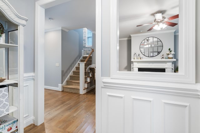 hall with ornamental molding, wood finished floors, and stairway