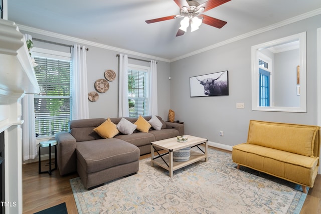 living area with wood finished floors, ceiling fan, ornamental molding, and baseboards