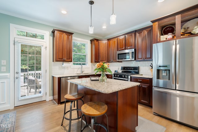 kitchen with stainless steel appliances, ornamental molding, light wood-style floors, backsplash, and hanging light fixtures