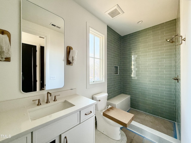 bathroom featuring a tile shower, vanity, and toilet