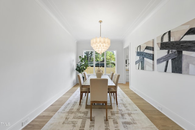 712 Daniels St, Raleigh, NC 27605 - dining room featuring baseboards, ornamental molding, a chandelier, and light wood-type flooring