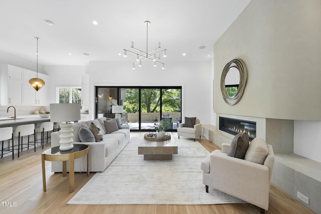 712 Daniels St, Raleigh, NC 27605 - living room with light wood-type flooring, a glass covered fireplace, recessed lighting, and a notable chandelier