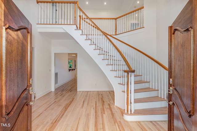 foyer featuring light wood-type flooring and a towering ceiling