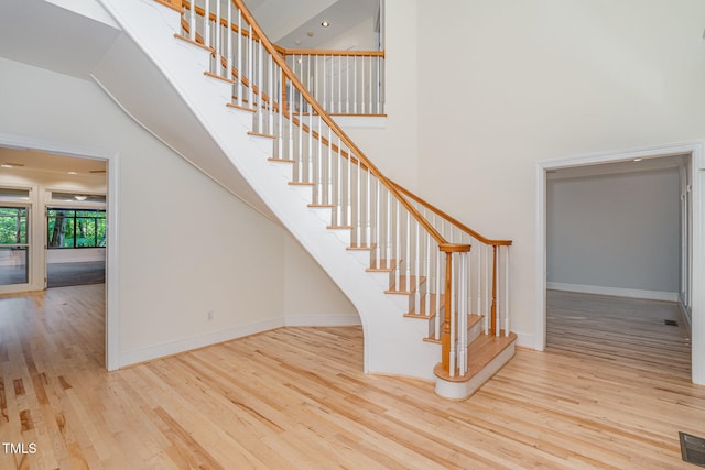 staircase featuring a high ceiling and hardwood / wood-style floors