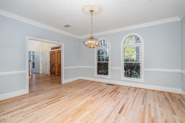 spare room with crown molding, a notable chandelier, and light wood-type flooring