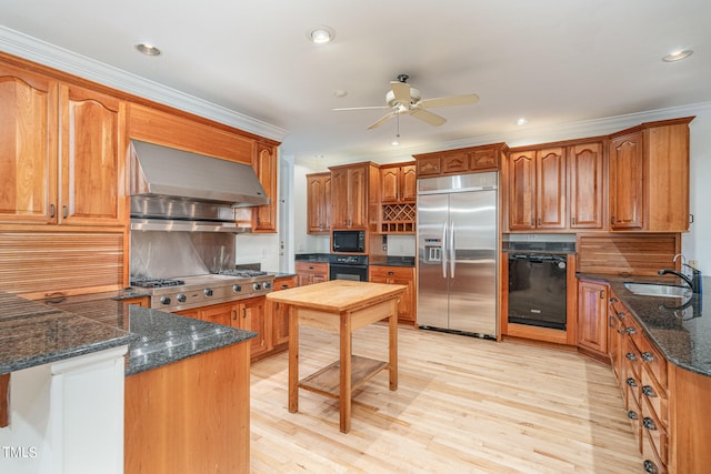 kitchen featuring wall chimney range hood, black appliances, sink, light wood-type flooring, and backsplash