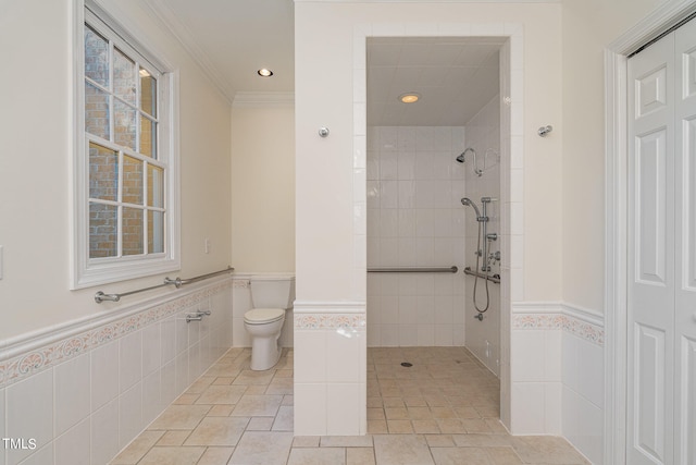 bathroom featuring toilet, crown molding, tile walls, and tiled shower