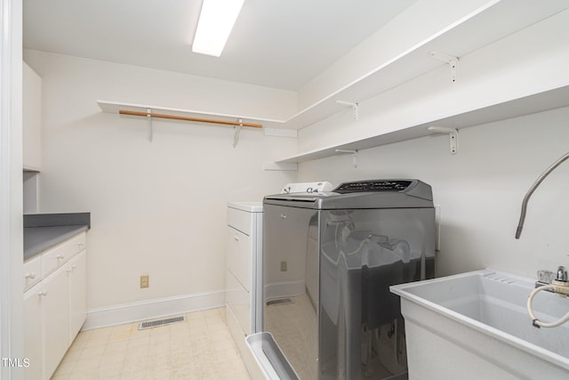 laundry area featuring cabinets, sink, and separate washer and dryer