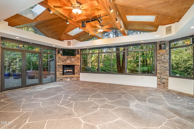 unfurnished living room featuring beam ceiling, wooden ceiling, a skylight, and ceiling fan