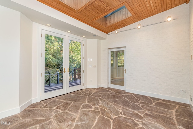 unfurnished room with brick wall, french doors, a skylight, and wooden ceiling