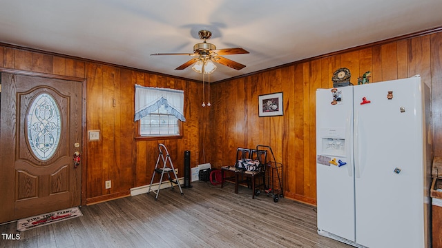 entrance foyer with wood-type flooring, wooden walls, ornamental molding, and ceiling fan