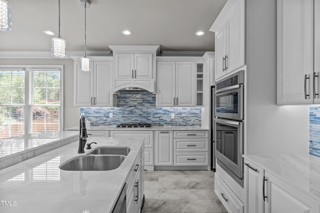 kitchen with pendant lighting, ornamental molding, sink, white cabinetry, and stainless steel appliances