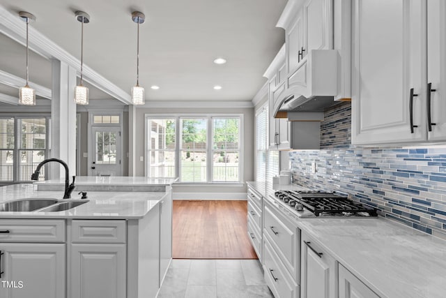 kitchen with light wood-type flooring, ornamental molding, light stone counters, and white cabinets